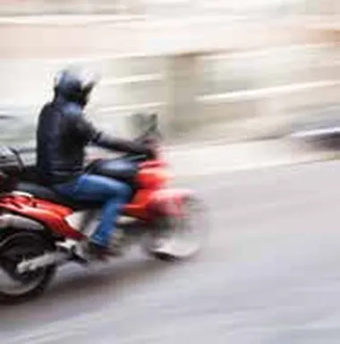 Photo of a motorcyclist riding fast beside cars
