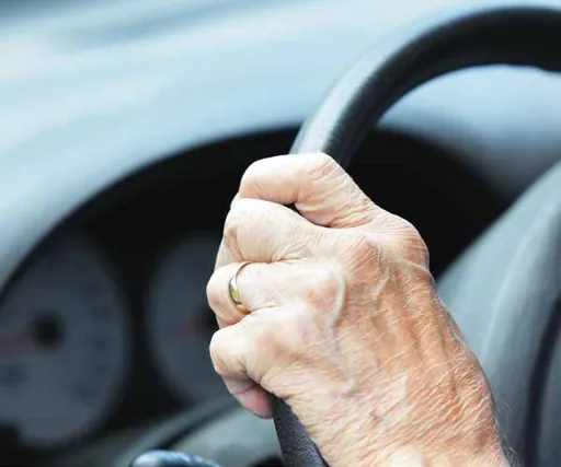 Close-up of an elderly person’s hands on a steering wheel