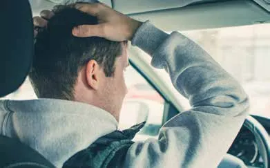 Stressed man in a car holding his head